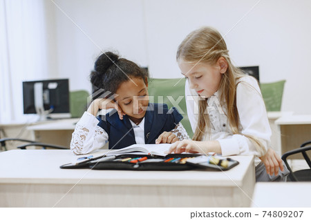 Two beautiful girls paint a notebook. Two beautiful girls paint a notebook. 74809207