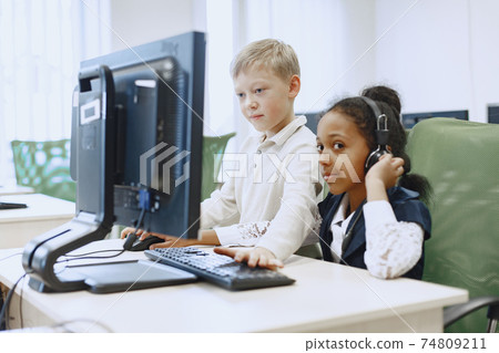 Children sit at computers in the classroom. 74809211
