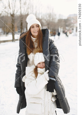 Mother and child in winter clothes play in winter park Mother and child in winter clothes play in winter park 74809330