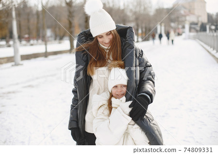 Mother and child in winter clothes play in winter park Mother and child in winter clothes play in winter park 74809331