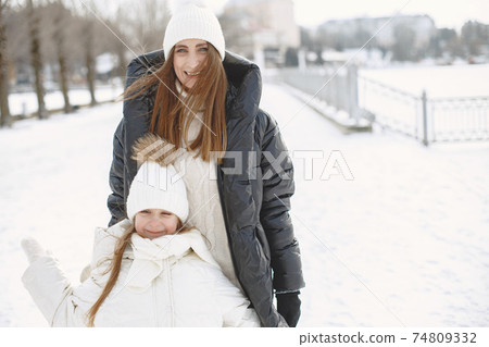 Mother and child in winter clothes play in winter park Mother and child in winter clothes play in winter park 74809332