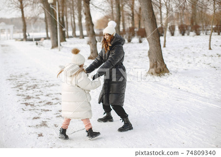 Mother and child in winter clothes play in winter park 74809340