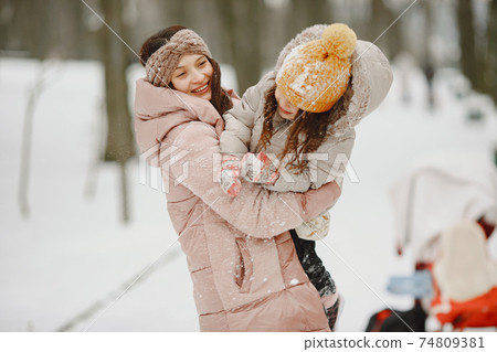 Mother and child in winter clothes play in winter park 74809381