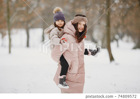 Mother and child in winter clothes play in winter park 74809572