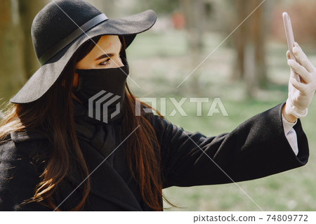 Woman in a mask stands on the street 74809772
