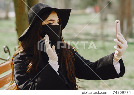 Woman in a mask stands on the street 74809774