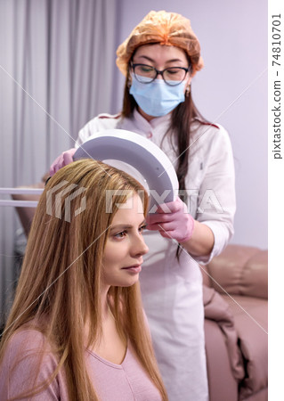professional serious doctor dermatologist holding magnifying glass for examination of female patient professional serious doctor dermatologist holding magnifying glass for examination of female patient 74810701
