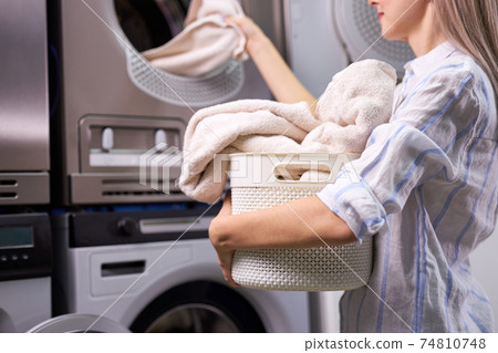 Housework: young caucasian woman doing laundry - putting out white garments from washing machine Housework: young caucasian woman doing laundry - putting out white garments from washing machine 74810748