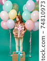 white girl 10 years old with a gift, pink, yellow, blue balloons for a holiday on a green background 74810973