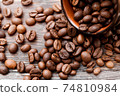 roasted brown coffee beans in a brown cup on a dark  background 74810984