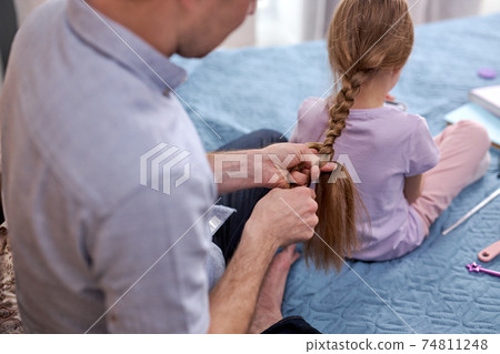 side profile photo father making braids to little girl in morning at home 74811248