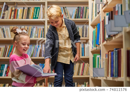 portrait of two school kids preparing for lesson in school library, reading textbooks together portrait of two school kids preparing for lesson in school library, reading textbooks together 74811576