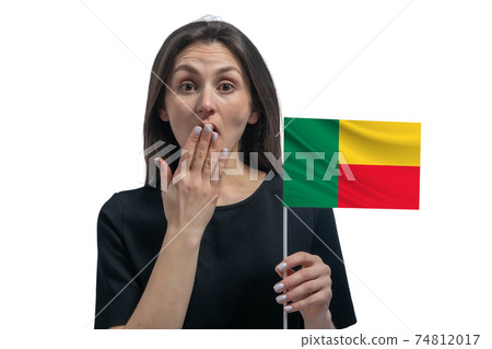 Happy young white woman holding flag of Benin and covers her mouth with her hand isolated on a white background 74812017