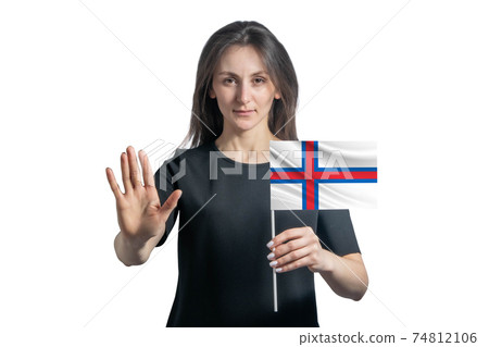 Happy young white woman holding flag of Faroe Islands and with a serious face shows a hand stop sign isolated on a white background Happy young white woman holding flag of Faroe Islands and with a serious face shows a hand stop sign isolated on a white background 74812106