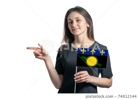 Happy young white woman holding flag Guadeloupe and points to the left isolated on a white background 74812144