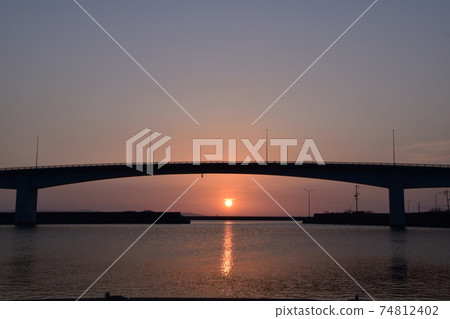 The rising sun rises between the bridge and the sea The rising sun rises between the bridge and the sea 74812402