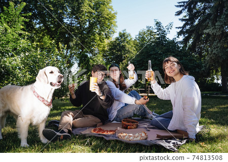 Company of beautiful young people and dog having an outdoor lunch. Company of beautiful young people and dog having an outdoor lunch. 74813508