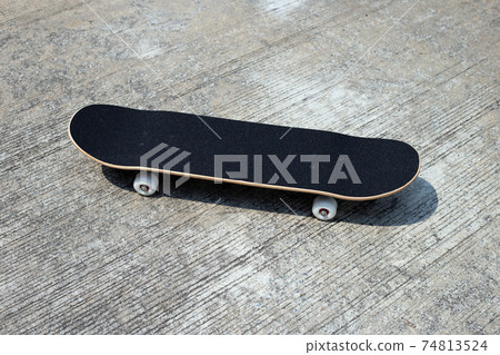 Black skateboard on cement ground. 74813524