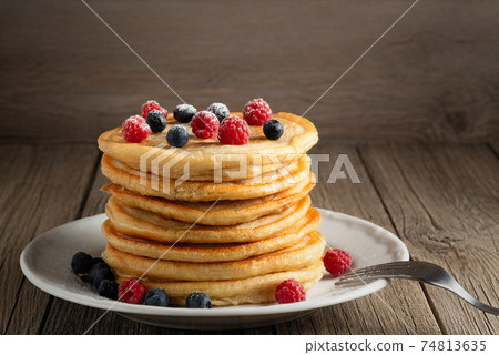 Stack of pancakes with fresh berries on a white plate on the table, copy space Stack of pancakes with fresh berries on a white plate on the table, copy space 74813635