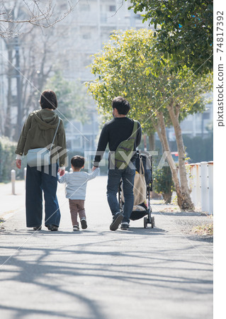 Family image of a couple raising children, parents and children walking in a residential area holding hands Family image of a couple raising children, parents and children walking in a residential area holding hands 74817392