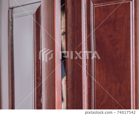Sad boy hide in closet, close-up view of blue eye in ajar door slit home wardrobe. Child emotions. Warning symptom sign, treatment help for childhood adolescent depression illness, fears, family life Sad boy hide in closet, close-up view of blue eye in ajar door slit home wardrobe. Child emotions. Warning symptom sign, treatment help for childhood adolescent depression illness, fears, family life 74817542