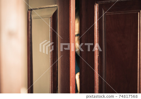 Sad boy hide in closet, close-up view of blue eye in ajar door slit home wardrobe. Child emotions. Warning symptom sign, treatment help for childhood adolescent depression illness, fears, family life Sad boy hide in closet, close-up view of blue eye in ajar door slit home wardrobe. Child emotions. Warning symptom sign, treatment help for childhood adolescent depression illness, fears, family life 74817568