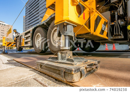 Crane car using outriggers at construction site 74819238