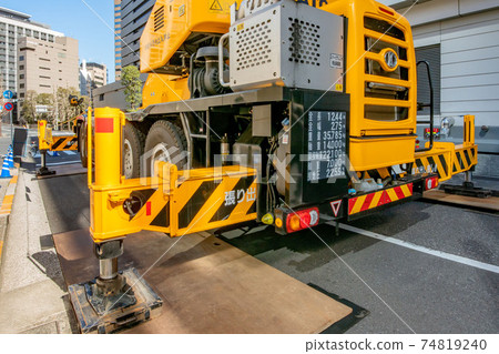 Crane car using outriggers at construction site 74819240