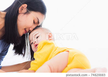 mother kissing her infant newborn baby in a white bed mother kissing her infant newborn baby in a white bed 74820083