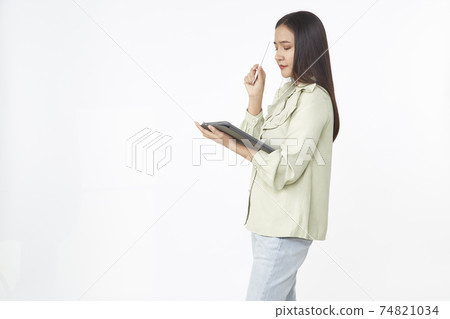 Beautiful young woman holding digital tablet and looking at camera with smile while standing. Wireless technology. 74821034