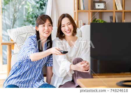 A young woman watching TV with her friends A young woman watching TV with her friends 74824618