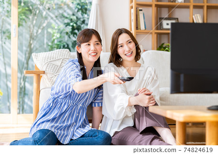 A young woman watching TV with her friends A young woman watching TV with her friends 74824619