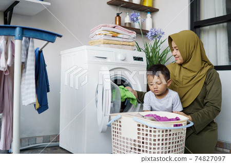 muslim asian woman doing laundry with her son 74827097
