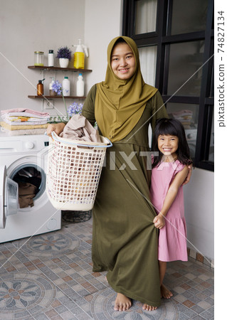muslim asian mother and child girl little helper in laundry room 74827134