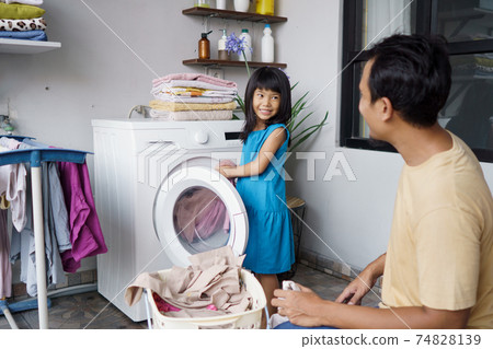 Happy family man father householder and child daughter in laundry with washing machine 74828139