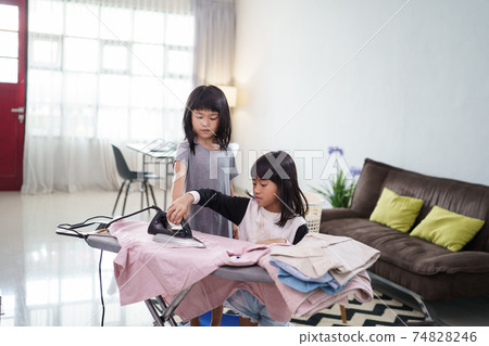 girl smiling happily as she doing the ironing at home girl smiling happily as she doing the ironing at home 74828246