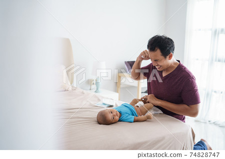 asian father changing his infant baby diaper asian father changing his infant baby diaper 74828747