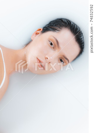 Close up female face in the milk bath with soft white glowing. Copyspace for advertising. Beauty, fashion, style, bodycare concept. Close up female face in the milk bath with soft white glowing. Copyspace for advertising. Beauty, fashion, style, bodycare concept. 74832592
