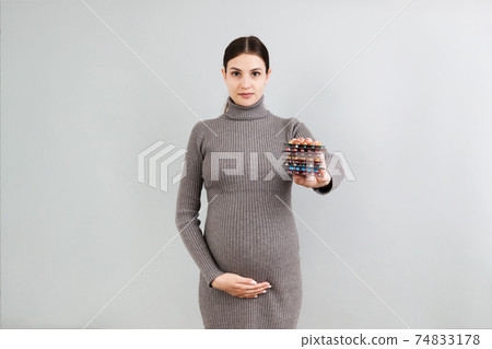 heap of blisters of pills in pregnant woman's hand at colorful background with copy space. Healthcare and treatment during pregnancy concept 74833178