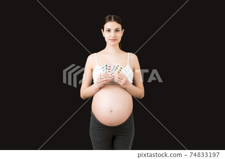 pregnant woman holding pill blisters at colorful background with copy space. Medical problems during pregnancy concept pregnant woman holding pill blisters at colorful background with copy space. Medical problems during pregnancy concept 74833197
