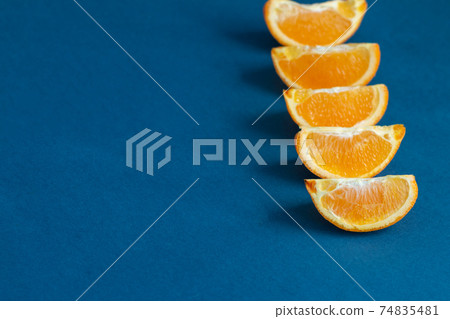 orange fruit slices on blue background, healthy food concept, empty space for text 74835481