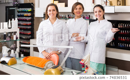 Smiling young team of nail technicians welcoming to modern beauty salon Smiling young team of nail technicians welcoming to modern beauty salon 74836531