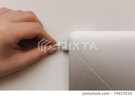 Top view of female hand holding the power plug of pc notebook. Laptop power 74837019