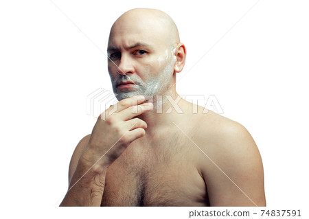 A bald white man prepares to shave his stubble. A man's face with shaving foam. A bald white man prepares to shave his stubble. A man's face with shaving foam. 74837591