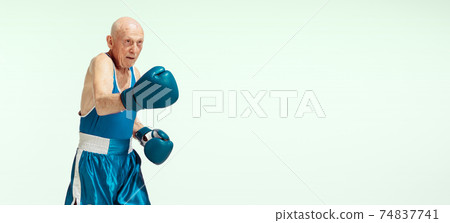 Senior man wearing sportwear boxing isolated on studio background. Concept of sport, activity, movement, wellbeing. Copyspace, ad. Senior man wearing sportwear boxing isolated on studio background. Concept of sport, activity, movement, wellbeing. Copyspace, ad. 74837741