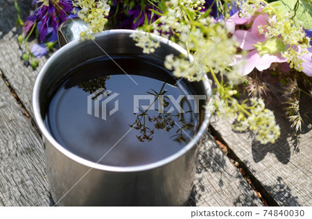 Tourism cup with tea, tea on the surface is a reflection of the flower 74840030