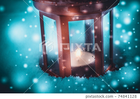 Red candle lantern with candle in snow during snowfall 74841128