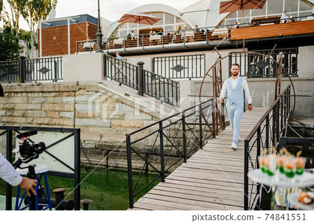 groom in blue suit goes to pier for wedding ceremony by water 74841551