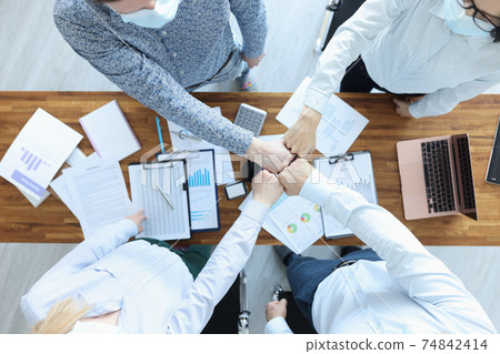Group of business people sitting at table and touching their fists tip view 74842414