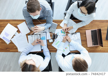 Group of business people in protective masks sitting at table top 74842417